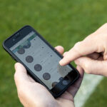 A close up of a mobile phone, the user is accessing the SRC irrigation controller through an app, adjusting infield sprinklers.