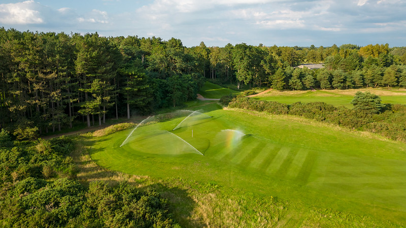 An aerial shot of sprinklers over a golf green.