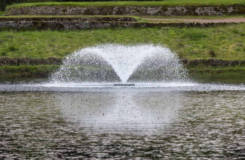 Surface fountain aerator operating on a pond to enhance water circulation and maintain healthy oxygen levels.